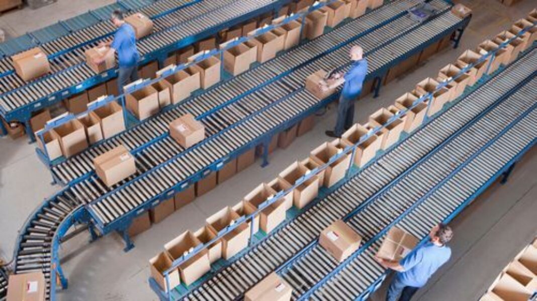 Top view of workers packing boxes on conveyor belts at a distribution wa